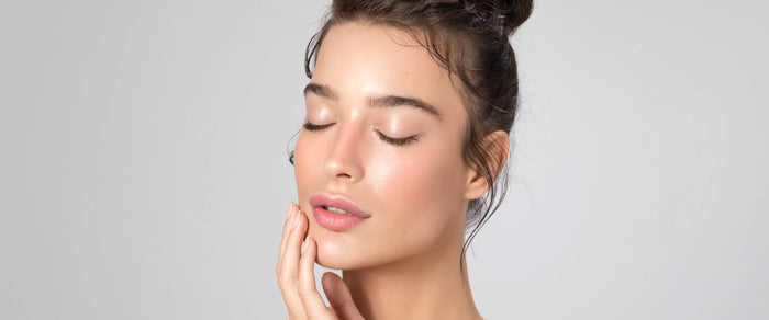 Femme aux yeux fermés, la main posée sur la joue, peau du visage lumineuse