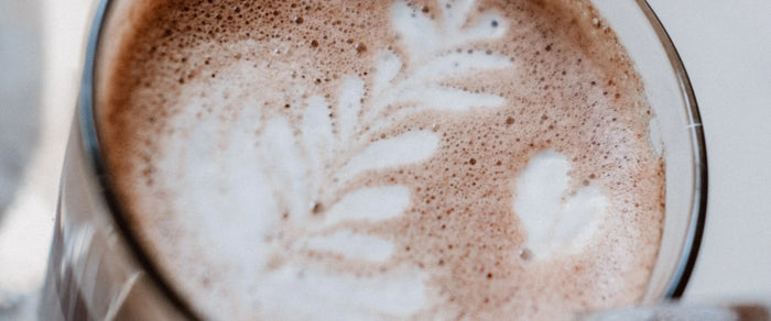 Chocolat chaud au collagène dans un verre, mousse de lait dessinée en forme de feuille