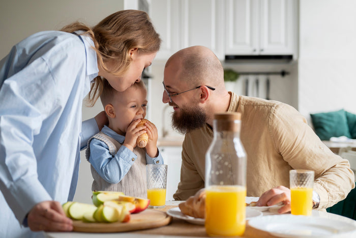 Famille au petit-déjeuner avec jus d'orange, source de vitamine C, pour préparer l'immunité à la rentrée