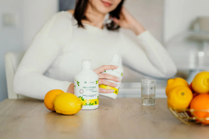 Flacon de Probiotique Liquide Vitamoon sur une table, à côté de citrons et d'un verre d'eau