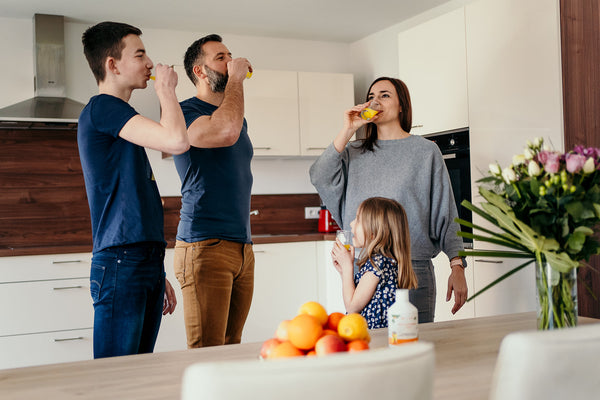 Famille buvant ensemble la Multivitamine Liquide Vitamoon dans la cuisine, illustrant un rituel quotidien d’énergie et de bien-être.