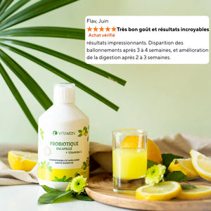 Bouteille de Probiotique Encapsulé Vitamoon avec vitamine C posée sur une table avec citrons et verre de jus, accompagnée d’un avis client mentionnant une meilleure digestion.